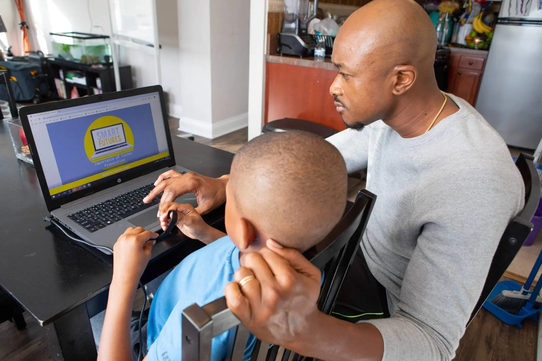 student and father look at a laptop screen with a lesson on it.