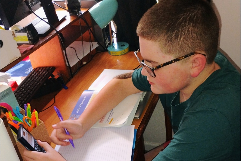 An insight PA student is doing their math work with a calculator in their hand.