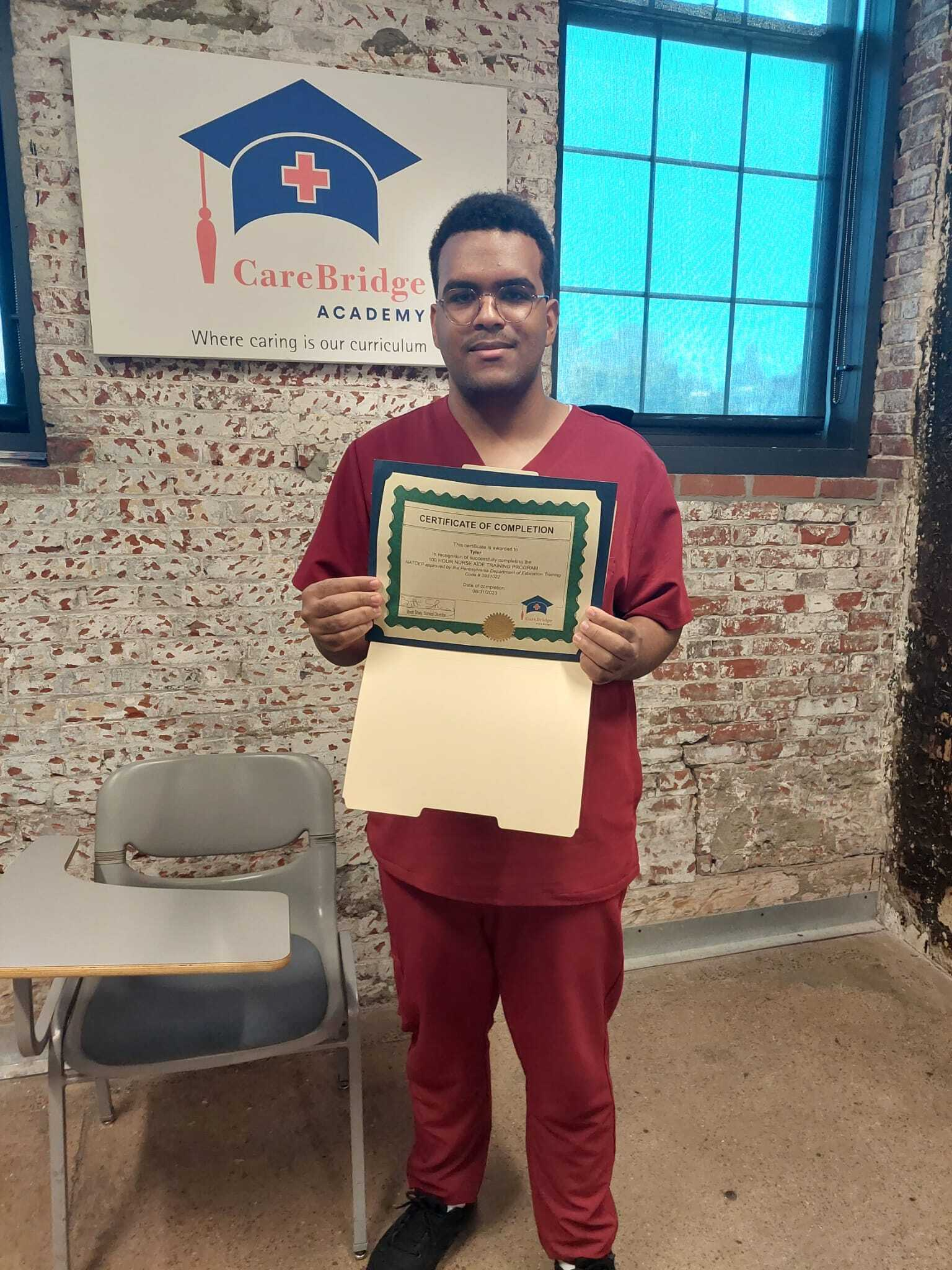An Insight PA student who recently completed his Certified Nurse Aid (CNA) holds up his certificate of completion.