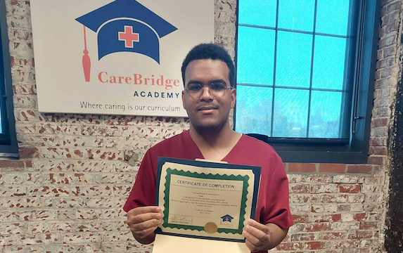 An Insight PA student who recently completed his Certified Nurse Aid (CNA) holds up his certificate of completion.