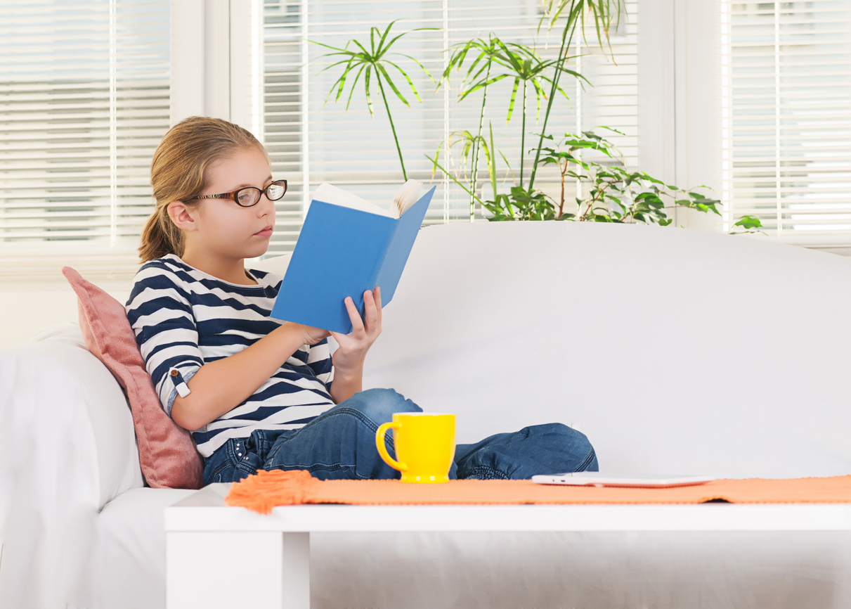 A student is sitting on a couch reading a book