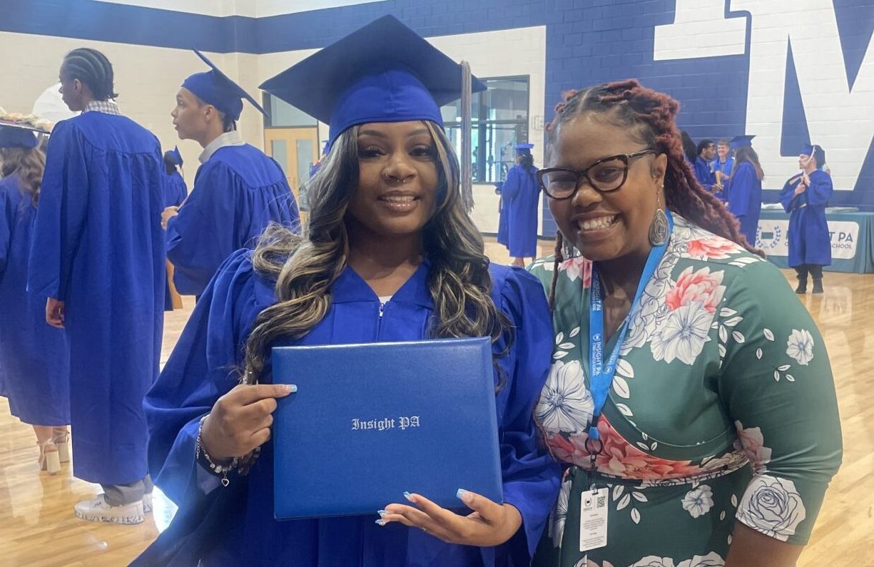 An Insight PA graduate poses with their diploma and an Insight PA staff member at the graduation ceremony.