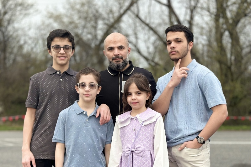 An Insight PA family, a father and four children, pose for the camera in front of a background of trees. 