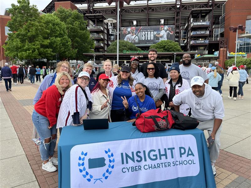 fdbedba0-784f-4029-bf94-8e332644529f Insight PA staff members smiling at a table outside of a Phillies Game.