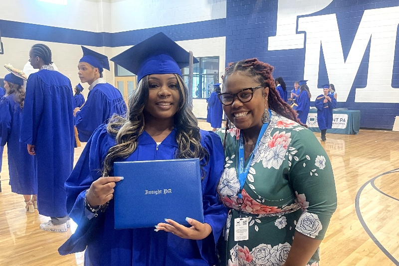 graduate smiles and holds diploma