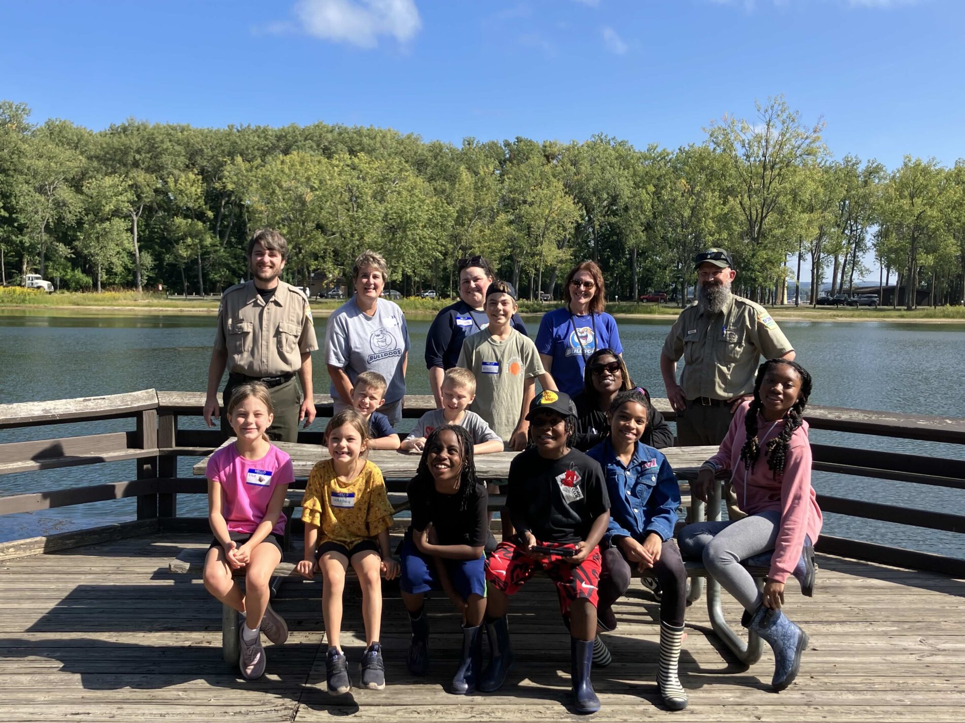 A group of students and their families pose on a lookout point at a lake.